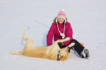 Girl on ice skates playing with dog