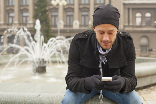 Happy Man With Mobile Phone In Front of Fountan