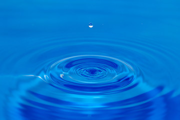 a drop of water falling in blue water