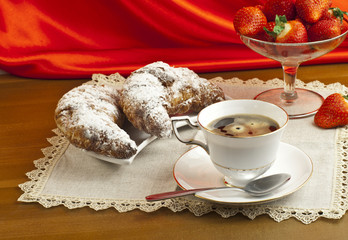 Breakfast with coffee , fresh croissants and strawberries.