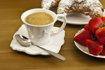 Breakfast with coffee , fresh croissants and strawberries.