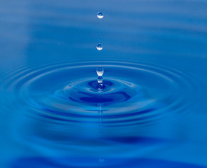 a drop of water falling in blue water
