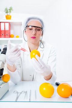Young female scientist injecting GMO into lemon in laboratory
