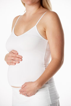 Close Up Studio Portrait Of 4 months Pregnant Woman Wearing Whit