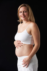 Portrait Of 4 months Pregnant Woman Wearing White On Black Backg