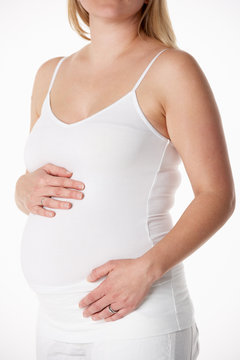 Close Up Studio Portrait Of 5 months Pregnant Woman Wearing Whit