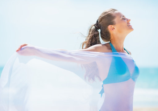 Happy young woman with parero rejoicing on beach