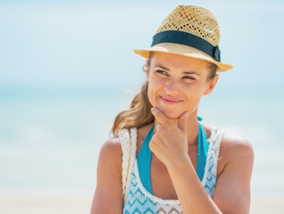 Thoughtful young woman in hat on beach