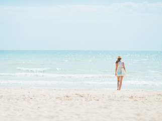 Fototapeta na wymiar Young woman standing on beach. rear view