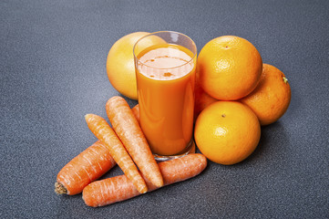 Orange and carrot juice in glass with ginger, fresh vegetables a