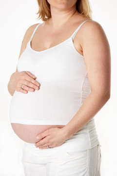 Close Up Studio Portrait Of 7 months Pregnant Woman Wearing Whit
