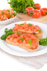 Delicious bruschetta with tomatoes on plate on table close-up