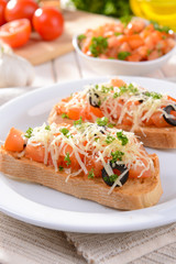 Delicious bruschetta with tomatoes on plate on table close-up
