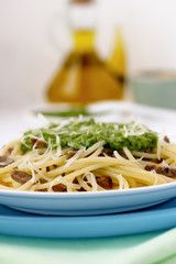 Italian pasta with pesto sauce on a blue plate.