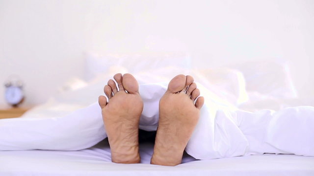 Man wiggling his toes under the duvet