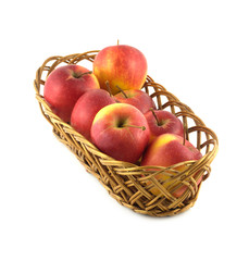 Ripe red apples in long brown wicker basket isolated