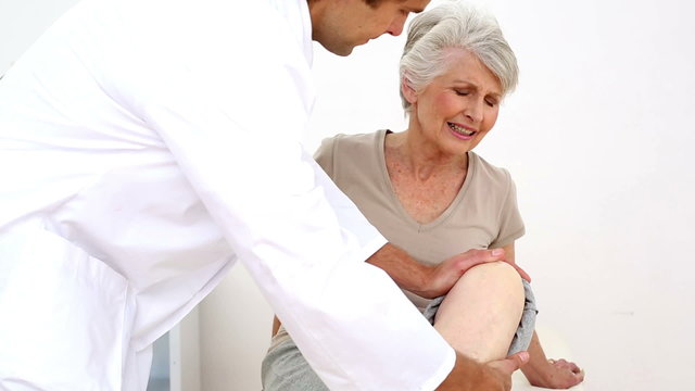 Injured patient wincing while doctor touches her knee