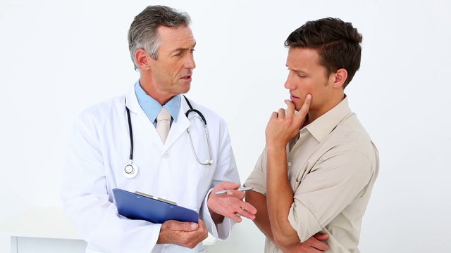 Patient speaking to his doctor holding clipboard