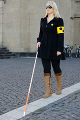 Blinde Frau mit Blindenstock und Armbinde