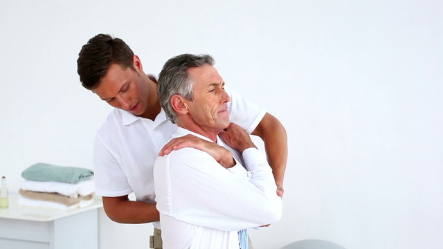 Businessman getting his shoulders aligned by physiotherapist