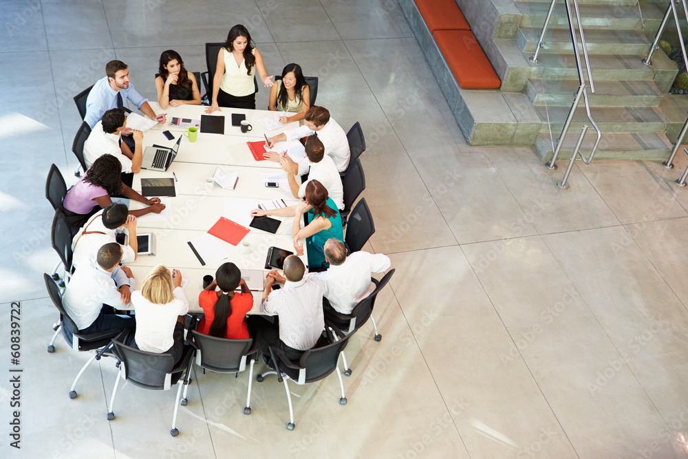 Wall mural businesswoman addressing meeting around boardroom table