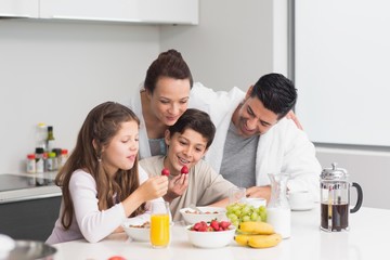 Happy kids enjoying breakfast with parents in kitchen