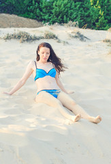 Pretty woman sitting on the beach sand.