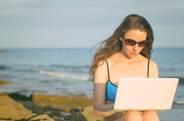 Woman with laptop working on the beach. Place for text.