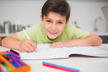 Smiling boy doing homework in kitchen