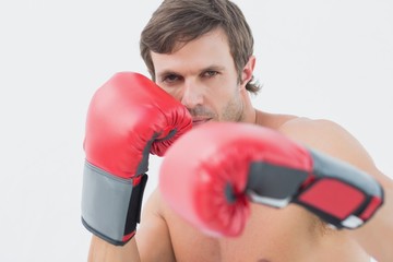 Portrait of a serious young man in red boxing gloves