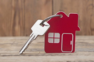 Symbol of the house with silver key on wooden background