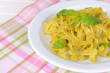Delicious pasta with pesto on plate on table close-up