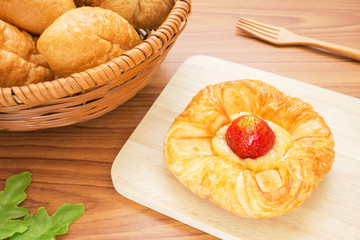 Danish pastry with strawberry on wooden plate