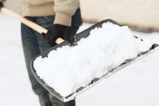 closeup of man shoveling snow from driveway
