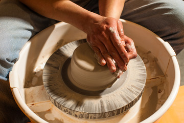 Hands working on pottery wheel , close up retro style