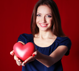 Attractive woman with heart, on red background