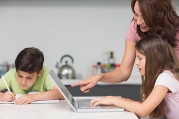 Mother with kids using laptop in kitchen