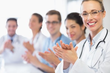 Happy doctor and team clapping - obrazy, fototapety, plakaty