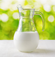 Jug of milk on nature background. Half full pitcher
