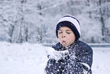 Niño soplando nieve de sus manos