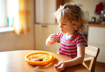 Little cute girl eating spaghetti