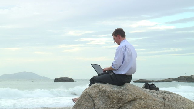 Gesch&auml;ftsmann arbeitet mit Laptop am Strand