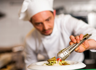 Chef arranging tossed salad in a white bowl