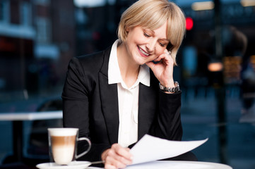 Female reviewing business report in cafe