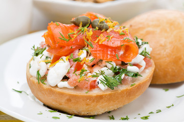 bun with cottage cheese, herbs, tomato and salmon, close-up