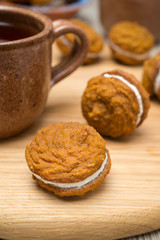 Pumpkin cookies with cream filling and a cup of tea, close-up