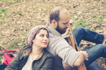 Portrait of woman leaning on his husband playing serenade on guitar in park