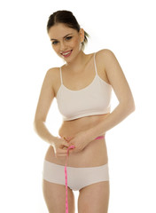 Fototapeta premium Beautiful young woman measuring her waistline