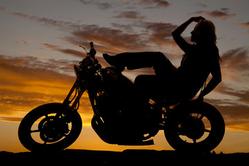 Fototapeta na wymiar Silhouette of woman on motorcycle hand hair leg up