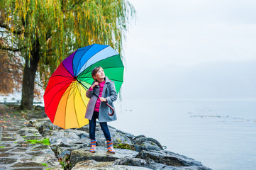 Cute little girl under big colorful umbrella